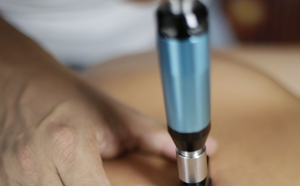 Handheld shockwave therapy applicator being applied to a patient's back